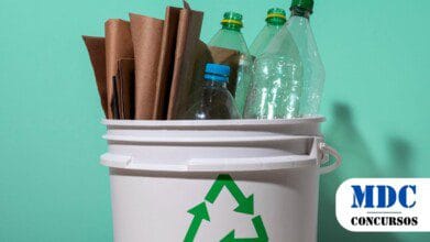 Processos Seletivos 4 Imagem de um balde branco com símbolo de reciclagem verde, contendo garrafas plásticas transparentes e papéis marrons enrolados. O fundo é verde claro e há sombras projetadas. A cena enfatiza a reciclagem e a sustentabilidade / PSS CIDASSP MG oferece 2 vagas p para Nível Fundamental II