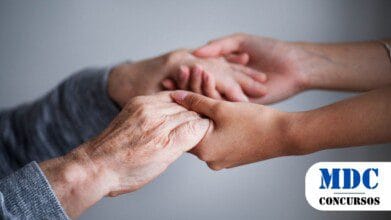 Processos Seletivos 7 Mãos de uma pessoa idosa, com pele enrugada, segurando delicadamente as mãos de uma pessoa mais jovem. A cena transmite carinho, apoio e conexão entre gerações, com um fundo neutro e suave que destaca o toque afetuoso entre as mãos / Processo Seletivo em Trindade GO oferece 79 vagas em diversas áreas da Assistência Social