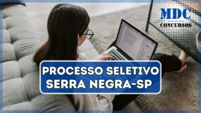Mulher de óculos sentada nasala de estar lendo no notebook | Serra Negra - SP oferece 29 vagas em Processo Seletivo com salários de até R$ 3.141,07