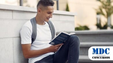 Um jovem lê um livro enquanto está sentado em degraus, desfrutando de um momento de tranquilidade e concentração / UNESP Botucatu abre concurso público com salários de até R$ 11,8 mil
