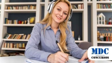 Mulher com fones de ouvido, registrando informações em um caderno, imersa em seu trabalho / UNESP lança concurso com salário de R$ 5,9 mil para Assistente de Suporte Acadêmico