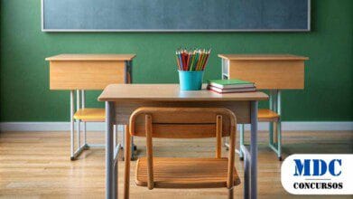 Sala de aula com carteiras e cadeiras de madeira, lousa verde ao fundo e um ambiente organizado. Na mesa da frente, há um pote azul com lápis de cor e alguns livros empilhados - Benjamin Constant (AM) Convoca 55 Aprovados em Processo Seletivo na Educação