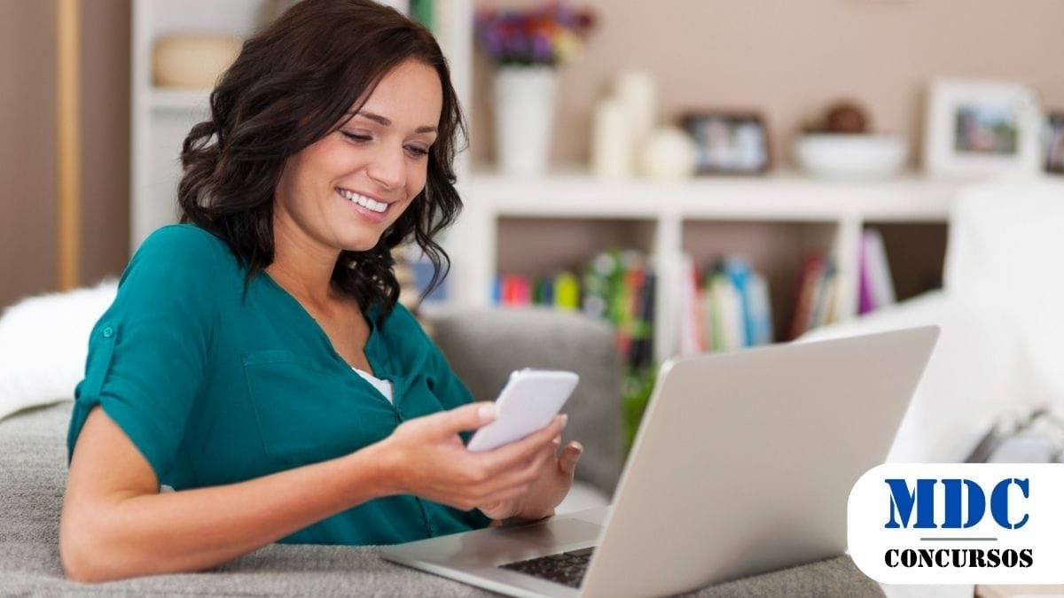 Borebi (SP) Abre Concurso com Salários de até R$ 4,5 mil e 10 Vagas 1 Mulher sorridente de blusa verde sentada em um sofá usando um notebook e um celular, aparentando estudar ou trabalhar. Ao fundo, uma estante com livros e itens decorativos. No canto inferior direito, o logotipo “MDC Concursos” indica relação com concursos públicos ou educação - Borebi (SP) Abre Concurso com 10 Vagas e Salários de até R$ 4,5 mil