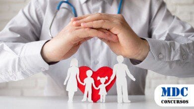 Médico com estetoscópio cruza as mãos em gesto de proteção sobre recortes de papel representando uma família com dois filhos, em frente a um coração vermelho, simbolizando cuidados médicos e saúde familiar - CISNORTE (MG) Lança Concurso com Mais de 10 Vagas