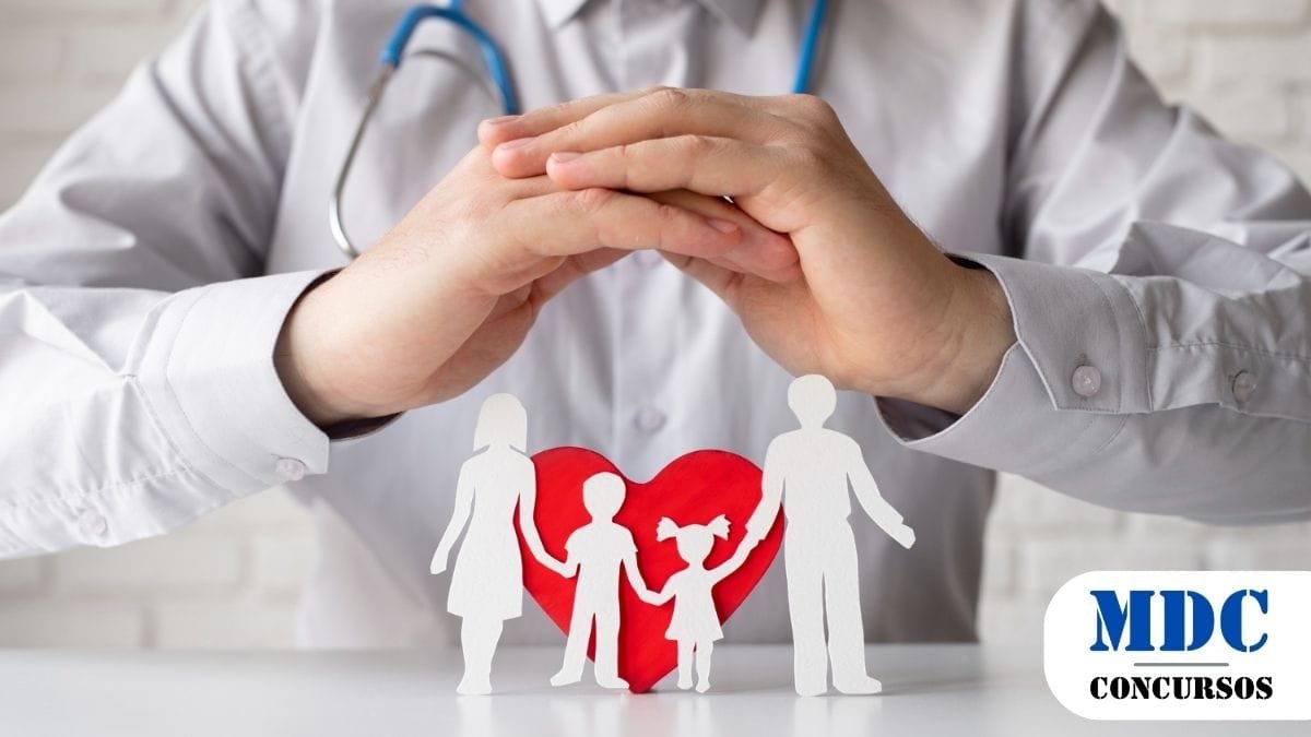 CISNORTE (MG) Lança Concurso com Mais de 10 Vagas 1 Médico com estetoscópio cruza as mãos em gesto de proteção sobre recortes de papel representando uma família com dois filhos, em frente a um coração vermelho, simbolizando cuidados médicos e saúde familiar - CISNORTE (MG) Lança Concurso com Mais de 10 Vagas