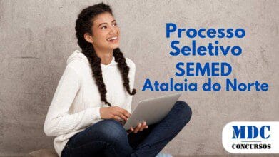 Jovem sorridente com cabelos cacheados em tranças, vestindo moletom branco, calça jeans e meias listradas, sentada no chão com as pernas cruzadas sobre uma almofada, segurando um laptop prata, olhando para o lado contra um fundo de parede cinza - SEMED Atalaia do Norte (AM) Lança Processo Seletivo 2025