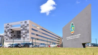 Fachada moderna da Assembleia Legislativa de Goiás com prédio administrativo ao fundo e placa institucional com brasão em primeiro plano. Foto: Divulgação/ALEGO