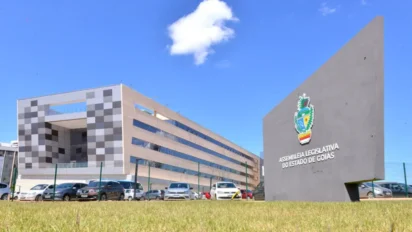Fachada moderna da Assembleia Legislativa de Goiás com prédio administrativo ao fundo e placa institucional com brasão em primeiro plano. Foto: Divulgação/ALEGO
