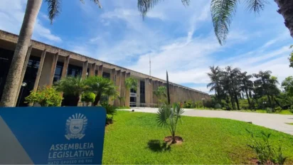 Assembleia Legislativa de Mato Grosso do Sul - ALMS com área verde, palmeiras e placa institucional em primeiro plano. Foto: Divulgação/ALMS (Aline Kraemer)