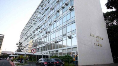 Fachada do prédio do Ministério da Saúde, com estrutura envidraçada e letreiro dourado na lateral.
