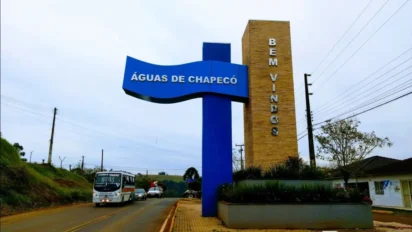 Placa de entrada de Águas de Chapecó com estrutura azul e totem vertical, localizada à beira de rodovia com veículos ao fundo. Foto: Divulgação/Prefeitura de Águas de Chapecó-SC