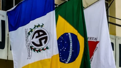 Bandeiras hasteadas do município de Amparo do Serra, do Brasil e de Minas Gerais, exibidas lado a lado em ambiente institucional. Foto: Divulgação/Prefeitura de Amparo do Serra-MG