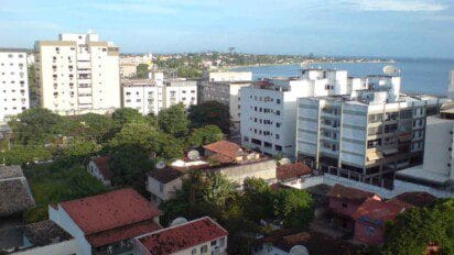 Vista do centro de Araruama-RJ com prédios residenciais, casas, áreas verdes e a lagoa ao fundo.