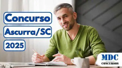 Homem de meia-idade com cabelos grisalhos curtos e barba rala sorri enquanto segura um lápis e escreve em um caderno sobre a mesa, vestindo suéter verde em ambiente interno com iluminação natural. Ao lado esquerdo da imagem estão os dizeres “Concurso Ascurra/SC 2025” em letras azuis com fundo branco. No canto inferior direito está o logotipo “MDC Concursos”