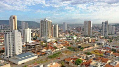 Processos Seletivos 7 Vista aérea de Barreiras-BA com prédios altos, casas residenciais e céu parcialmente nublado ao fundo.