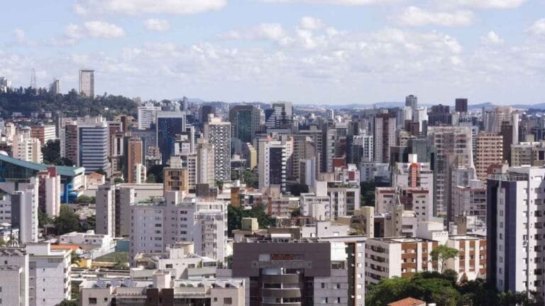 Vista panorâmica de Belo Horizonte com diversos prédios altos sob céu com nuvens claras