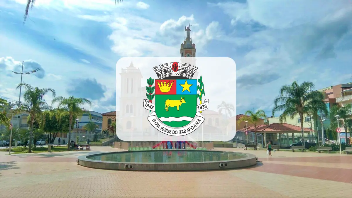 Bom Jesus do Itabapoana/RJ abre seleção com 34 vagas imediatas 1 Fotografia de uma praça urbana ensolarada em Bom Jesus do Itabapoana, com palmeiras e um chafariz circular em primeiro plano. Ao centro, destaca-se o brasão oficial do município sobreposto à imagem. Ao fundo, sob um céu azul com nuvens, observa-se a arquitetura local e o topo de uma igreja com uma estátua.
