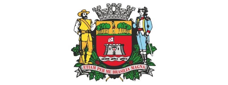 Brasão de armas do município de Jundiaí, com escudo vermelho, figuras de bandeirante e soldado, coroa mural e lema em latim na faixa inferior.