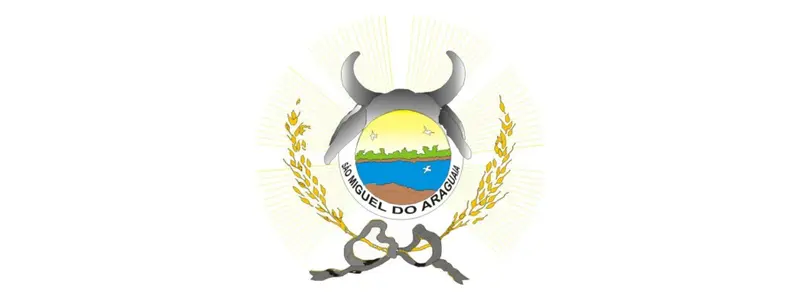 Brasão de São Miguel do Araguaia com escudo central exibindo paisagem, rio e sol, ladeado por ramos dourados e símbolos agrícolas no topo