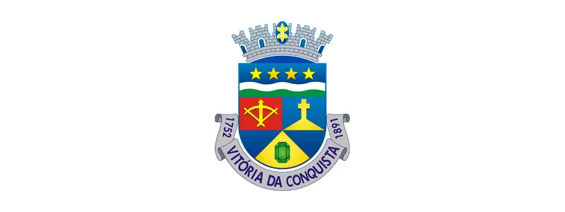 Brasão oficial de Vitória da Conquista com escudo colorido dividido em campos, estrelas na parte superior, símbolos religiosos e históricos, coroado por muralha e com faixa inferior contendo o nome do município e datas.