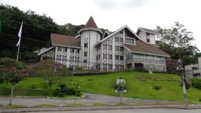 Prédio da Prefeitura de Brusque em estilo enxaimel, localizado em área verde com jardins e árvores ao redor. Foto: Andrevruas/Wikipédia