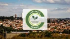 Logotipo do Consórcio CEMMIL sobreposto a uma vista panorâmica de uma cidade com casas e vegetação sob um céu nublado.