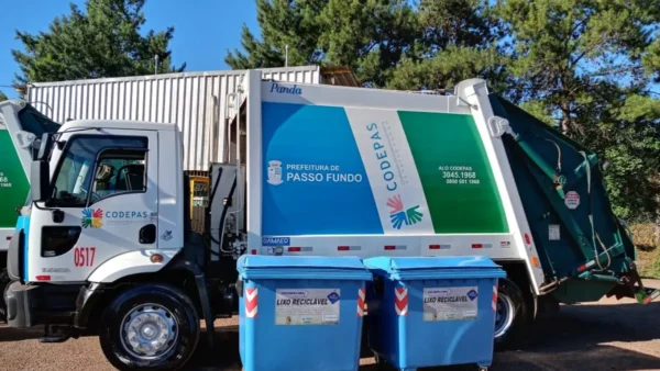 CODEPAS Passo Fundo/RS abre concurso com salários de até R$ 2.703,69 2 Caminhão de lixo branco com detalhes em azul e verde da CODEPAS e Prefeitura de Passo Fundo estacionado ao lado de dois contêineres azuis para lixo reciclável sob a luz do dia. Foto: Divulgação/CODEPAS
