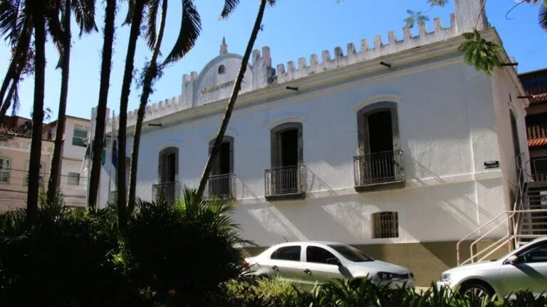 Prédio histórico branco da Câmara Municipal de Angra dos Reis com janelas altas, pequenos balcões e carros estacionados em frente. Foto: Divulgação/Câmara Municipal de Angra dos Reis-RJ