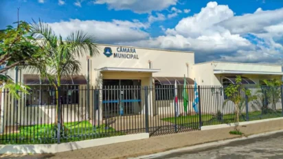 Fachada da Câmara Municipal de Arceburgo-MG com portão gradeado, bandeiras hasteadas e céu azul com nuvens ao fundo. Foto: Divulgação/Prefeitura de Arceburgo-MG