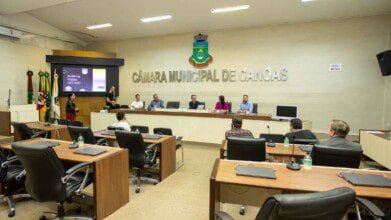 Sessão na Câmara Municipal de Canoas com vereadores e participantes sentados em mesas durante audiência pública sobre a LDO 2024.