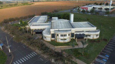 Vista aérea da Câmara Municipal de Cerquilho, em São Paulo, com edifício moderno cercado por áreas verdes, vagas de estacionamento e vias asfaltadas.