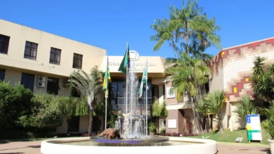 Fachada da Câmara Municipal de Goiânia com fonte central, bandeiras hasteadas e vegetação ao redor sob céu azul. Foto: Divulgação/Câmara Municipal de Goiânia/GO
