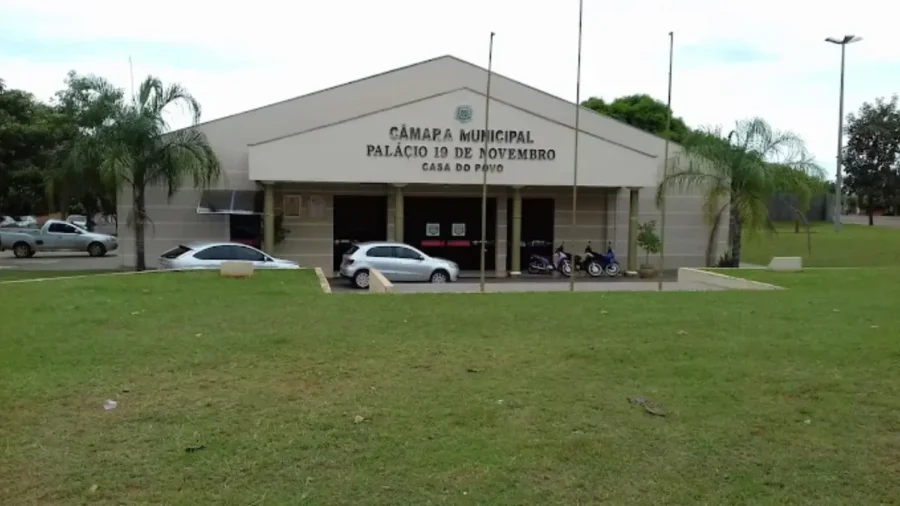 Fachada da Câmara Municipal de Teodoro Sampaio, o Palácio 19 de Novembro, com gramado frontal e carros estacionados.