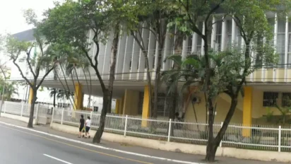 Fachada da Câmara Municipal de Volta Redonda/RJ com estrutura moderna, colunas verticais, árvores na calçada e pessoas caminhando pela rua. Foto: Divulgação/Câmara Municipal de Volta Redonda-RJ