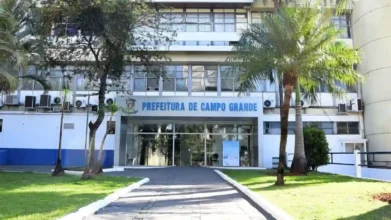 Fachada da Prefeitura de Campo Grande com letreiro azul, entrada envidraçada, árvores e jardim na frente. Foto: Divulgação/Prefeitura de Campo Grande-MS