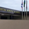 Fachada da Prefeitura Municipal de Canudos com letreiro em destaque e mastros com bandeiras em frente ao prédio sob céu nublado.