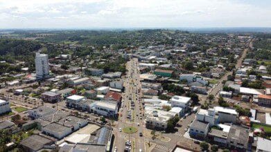 Vista aérea da cidade de Capanema-PR com avenida central, prédios comerciais, residenciais e área verde ao fundo. Foto: Divulgação/Prefeitura de Capanema-PR
