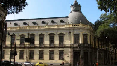 Fachada histórica do Colégio Pedro II com arquitetura clássica, janelas altas, detalhes ornamentados e grande cúpula na esquina da construção. Foto: Cyro A. Silva/Wikipédia