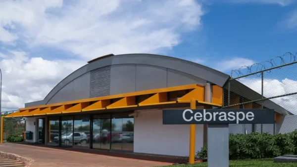 Fachada do prédio do Cebraspe com estrutura moderna, detalhes em amarelo e placa com o nome da instituição em área externa. Foto: CEBRASPE/Divulgação/Natália Valarini