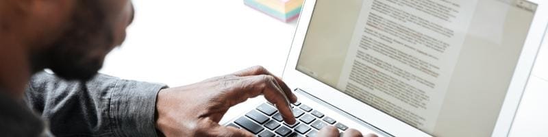 Prefeitura de Três Rios abre processo seletivo com 49 vagas 2 Pessoa digitando em um laptop, com foco nas mãos no teclado e na tela exibindo um texto.