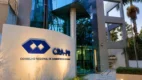 Placa com logotipo do CRA-PR na entrada do prédio de vidro, sede do concurso CRA PR
