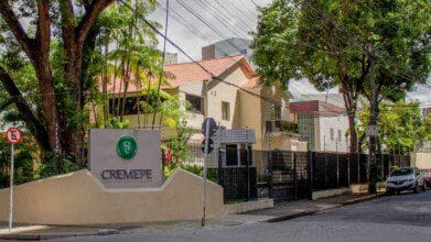 Fachada da sede do CREMEPE com muro, portão preto, placa com logotipo e árvores ao redor em rua arborizada. Foto: Divulgação/CREMEPE