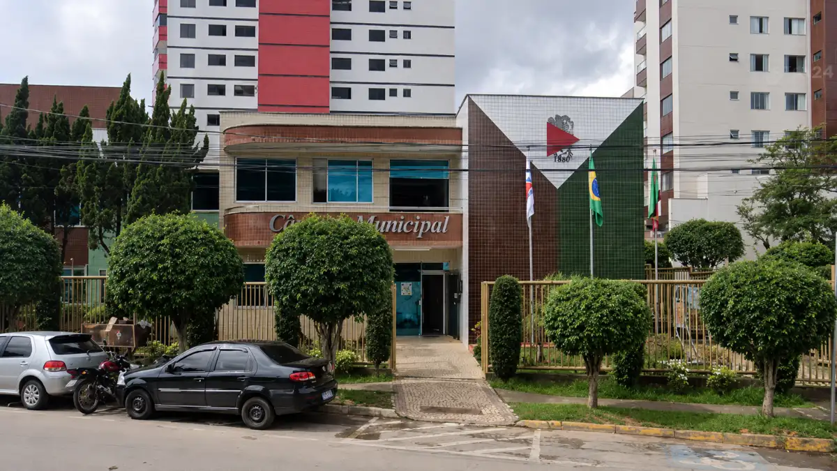 Concurso Câmara de João Monlevade MG tem banca definida para 13 vagas imeditas 1 Fachada da Câmara Municipal com placa e bandeiras ao fundo, referente ao concurso Câmara de João Monlevade MG