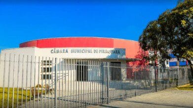 Fachada da Câmara Municipal de Piraquara-PR com muro, portão metálico e placa com o nome da instituição. Foto: Divulgação/Câmara Municipal de Piraquara-PR