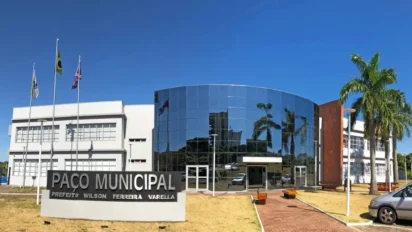 Fachada de vidro do Paço Municipal com bandeiras e palmeiras, sede do concurso Cianorte PR