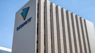 Fachada do prédio da Dataprev com logotipo colorido e céu azul no concurso Dataprev
