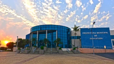 Fachada azul e envidraçada da Prefeitura de Indaiatuba, sede do concurso Indaiatuba SP, ao pôr do sol