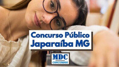 Fotografia em foco seletivo mostra uma jovem de pele clara usando óculos de armação marrom e blusa clara rendada, apoiando delicadamente a cabeça no braço sobre a mesa em ambiente de estudo. No centro da imagem aparece uma tarja branca com bordas escuras contendo a frase “Concurso Público Japaraíba MG” em letras grandes e azuis, transmitindo informação sobre um edital. Abaixo da tarja, em menor proporção, está o logotipo retangular da “MDC Concursos” em azul sobre fundo branco, completando o visual promocional