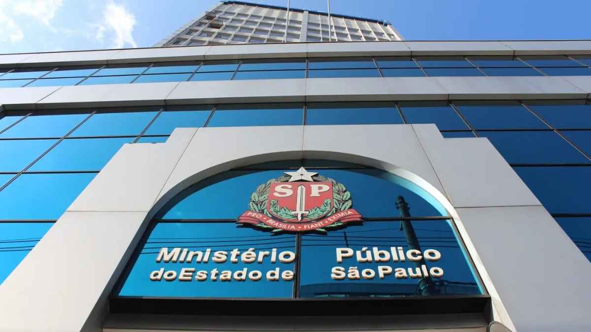 Fachada do edifício moderno do Ministério Público de São Paulo, com janelas de vidro azul espelhado, brasão do Estado e inscrição oficial em destaque em referência ao Concurso MPSP