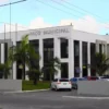 Fachada do Paço Municipal de Matinhos, sede da prefeitura responsável pelo concurso Matinhos PR, com palmeiras e estacionamento ao fundo